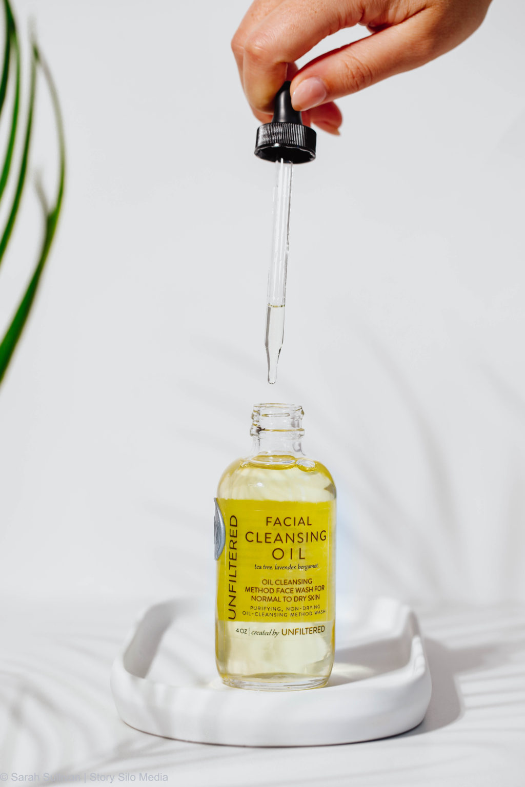 Image of a woman unscrewing a bottle of Unfiltered facial cleaning oil