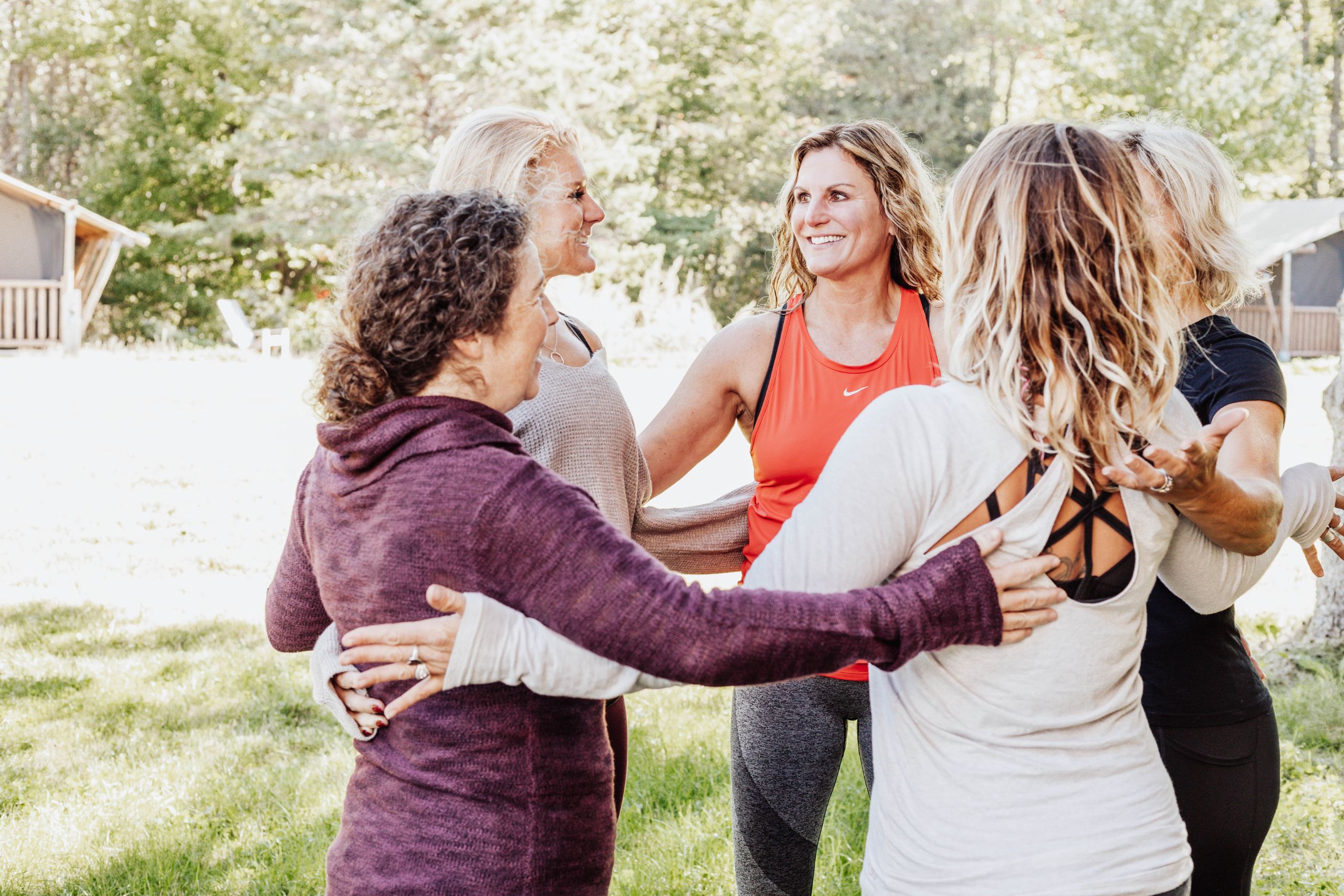 A group of yoga participants smile at eachother and stand in a circle