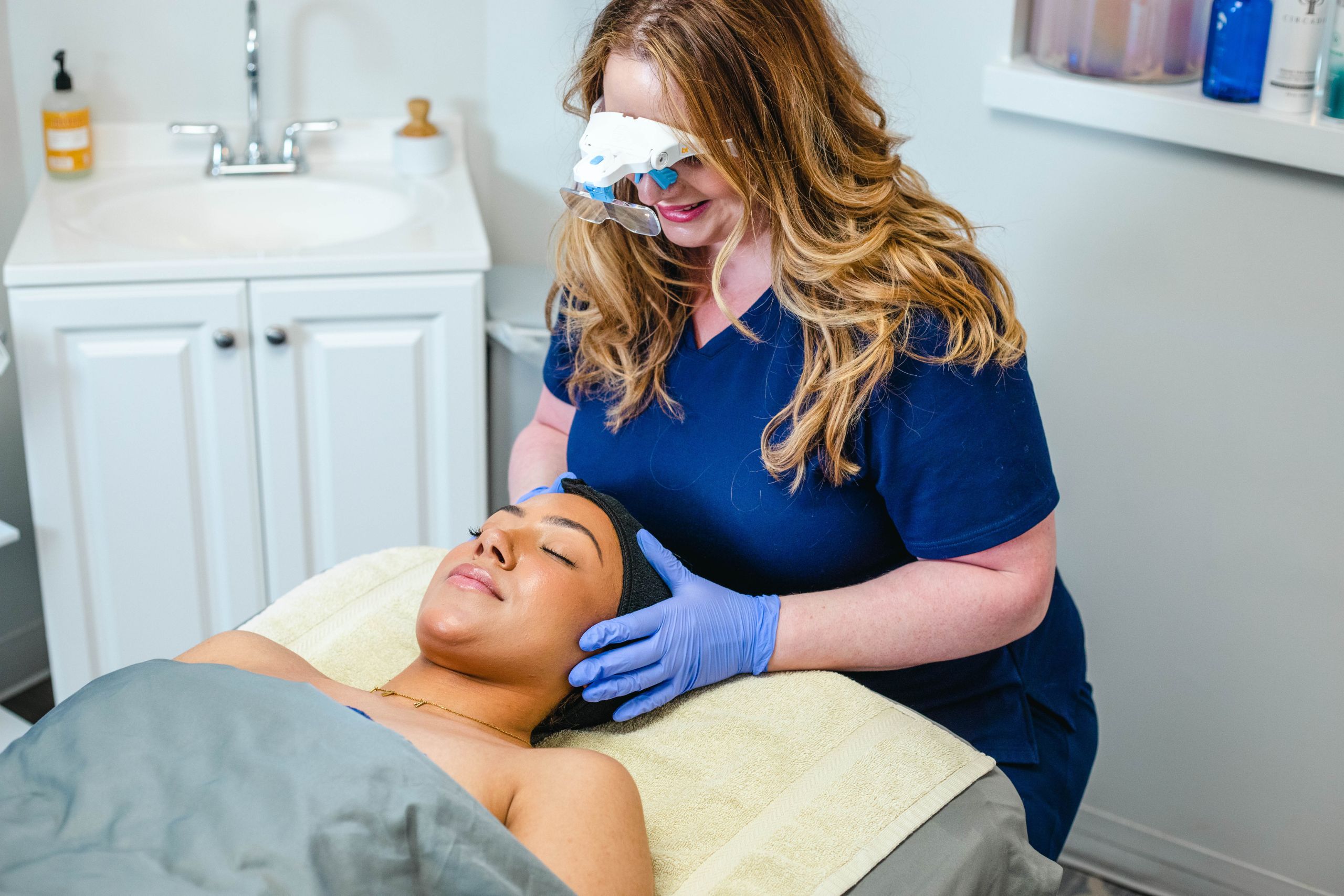 A medspa doctor holds a patient's head while she examines her face.