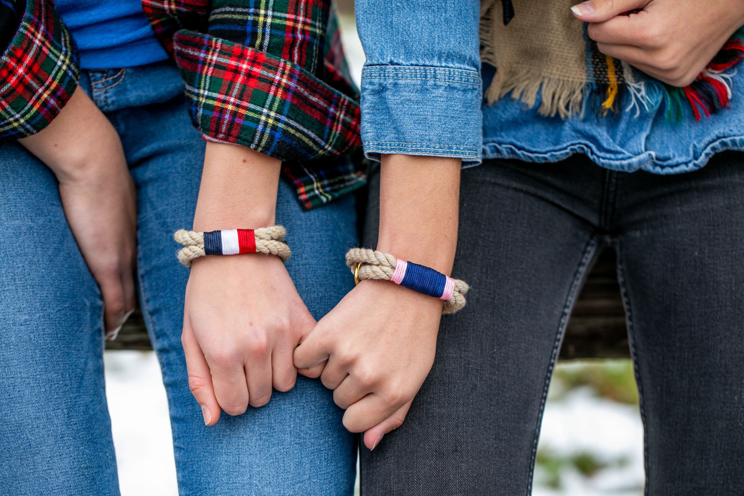 A photo of two young women wearing bracelets and holding pinkies
