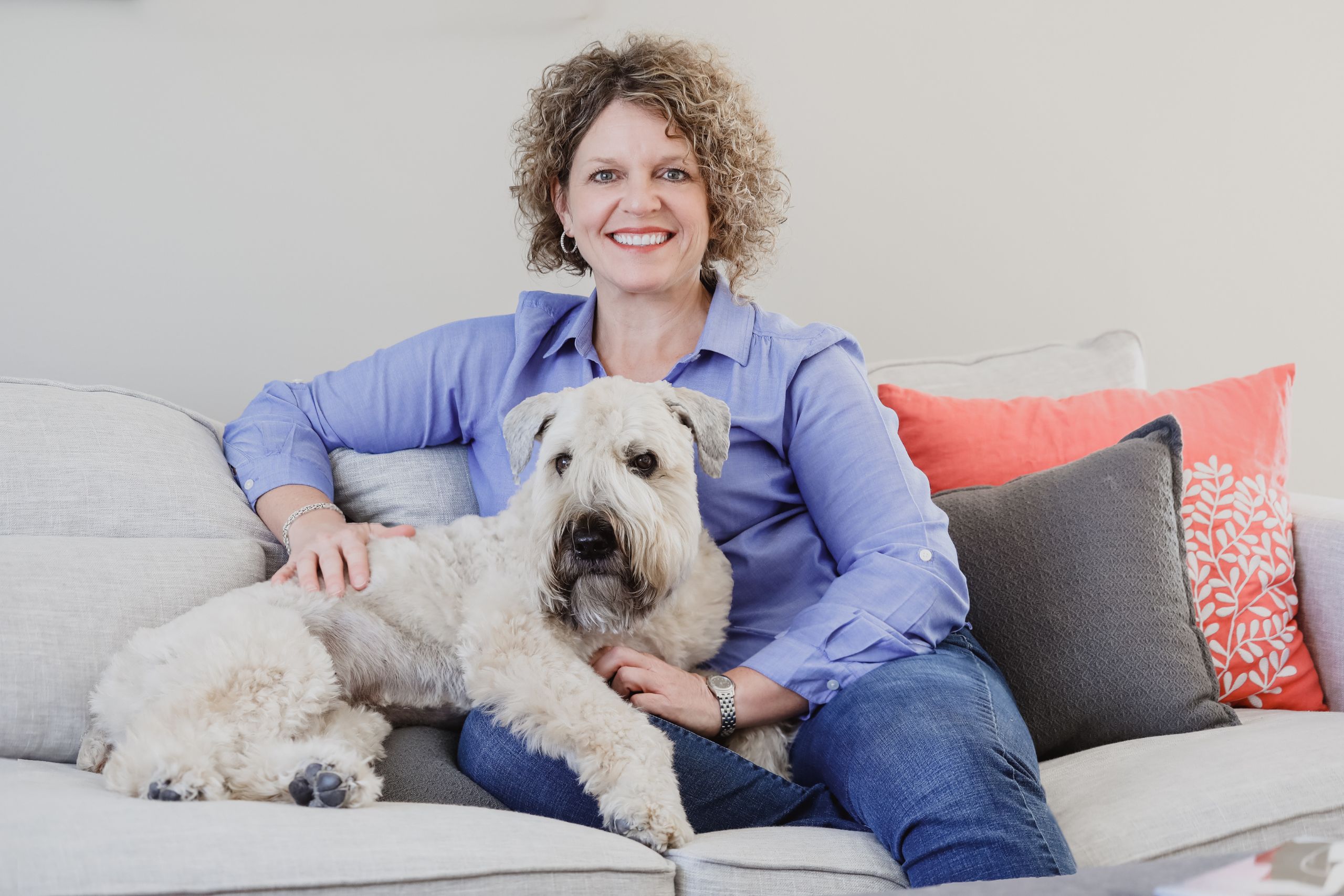 A woman poses with her dog on a couch