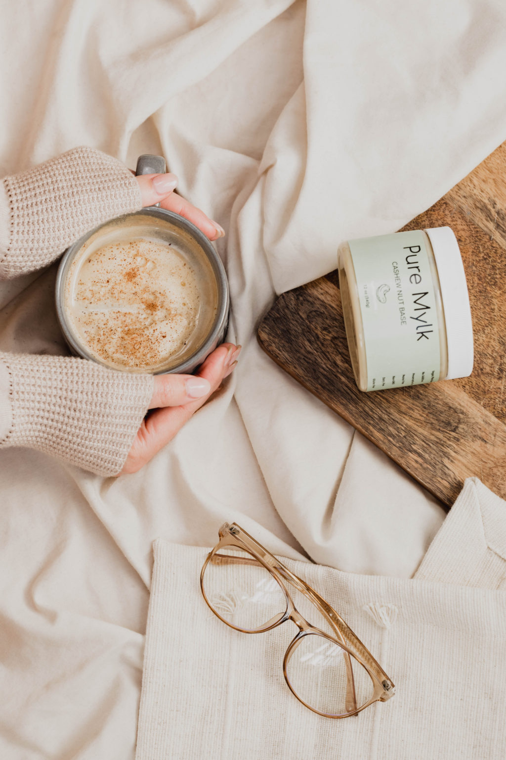 Image of Pure Mylk Chase nut base cream. Hands grip a mug with the cream inside.