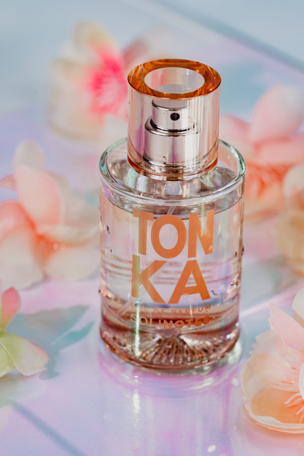 Image of Tonka perfume. Flowers are in the background.