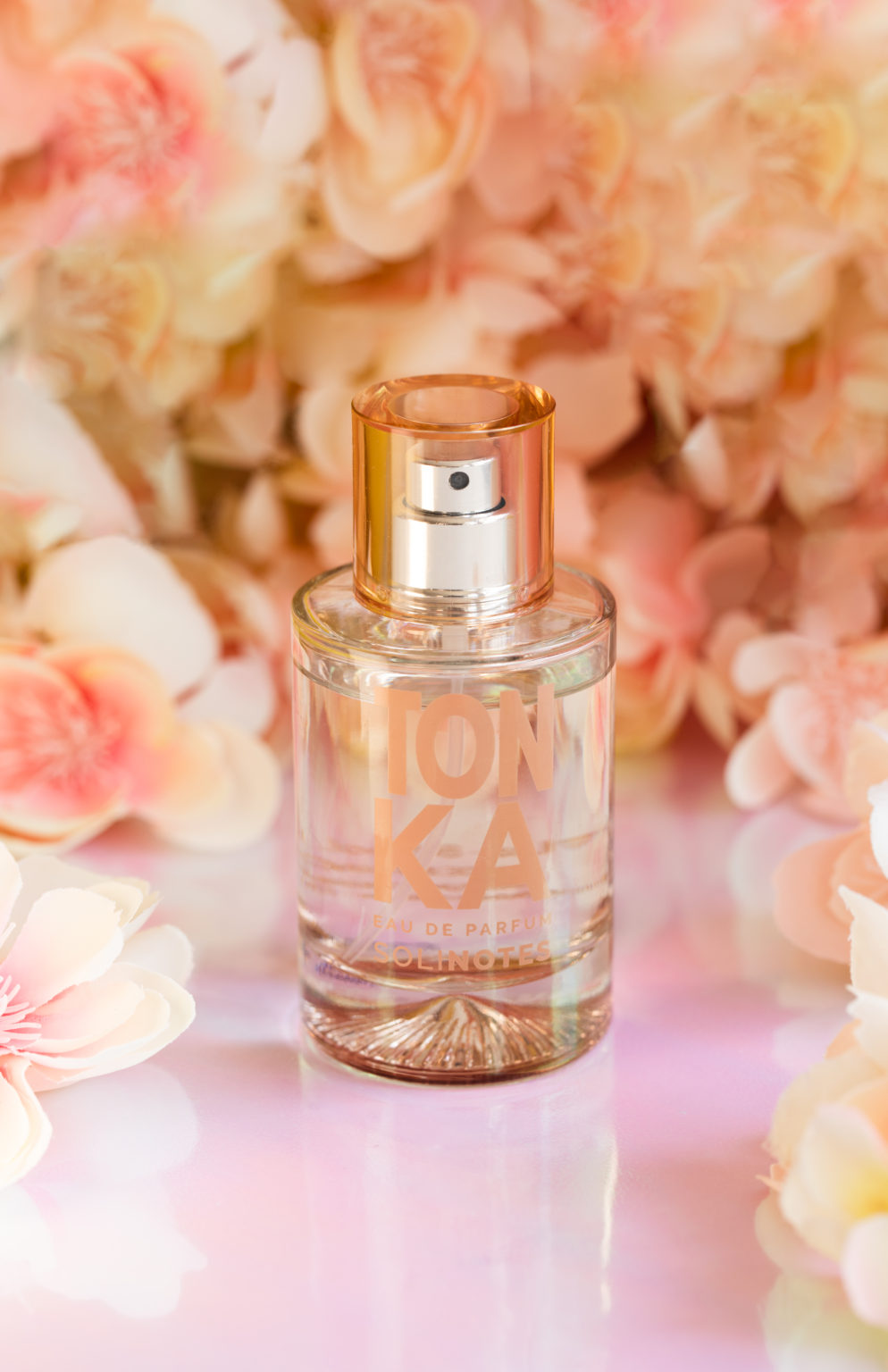 Image of Tonka perfume. Flowers are in the background.